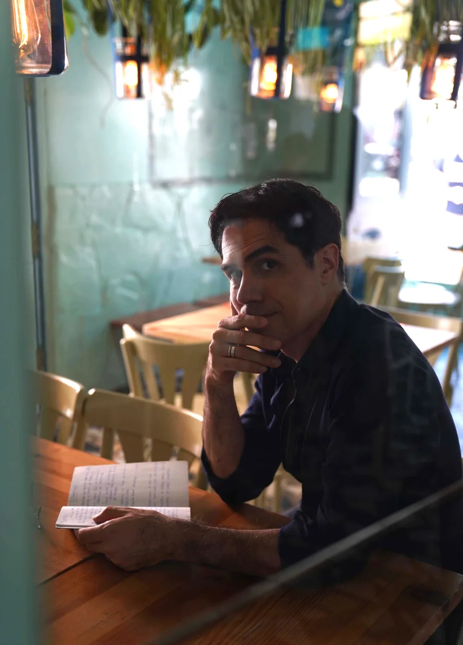 Diego Sabanés escribiendo en un cuaderno, sentado en un bar.